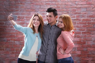 Selfie cep telefonu ile tuğla duvar arka plan üzerinde alan genç insanlar