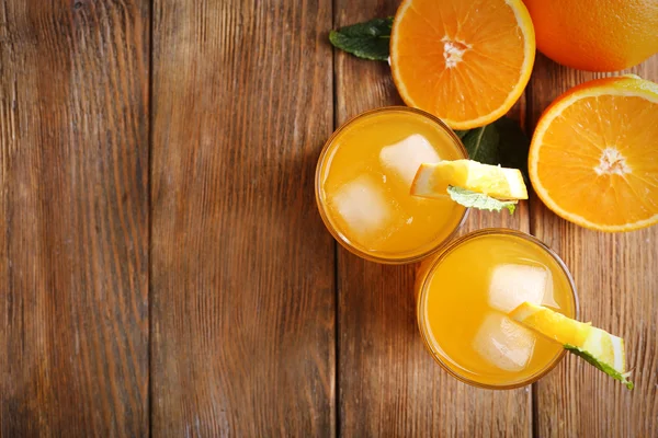 Zwei Orangensäfte mit Eis und Orange auf Holztischhintergrund, Blick von oben — Stockfoto