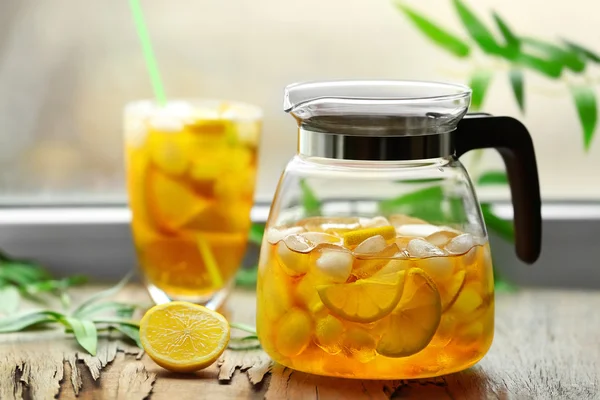 Glass and jar of iced tea with lemon on a windowsill — Stock Photo, Image