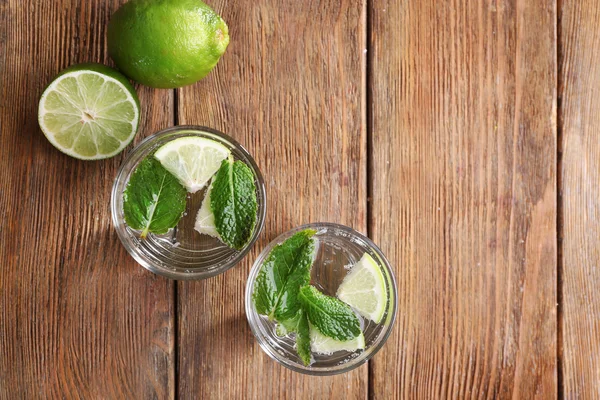 Frische Cocktails mit Minze, Eis und Limette auf Holztischhintergrund, Blick von oben — Stockfoto