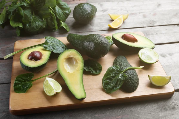 Avocado affettato con lime e spinaci sul tagliere di legno — Foto Stock