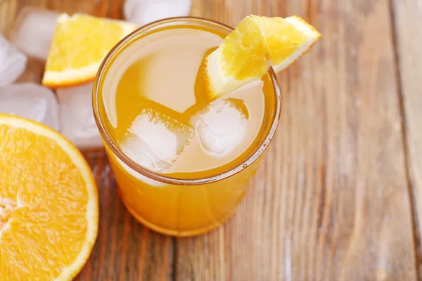 Апельсиновый сок с кубиками льда и апельсина на фоне деревянного стола, крупным планом — стоковое фото