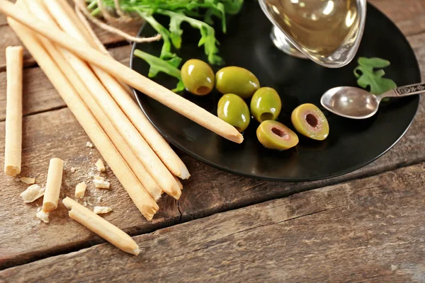 Tyčinky s rukolou, olej a olivy na desce — Stock fotografie