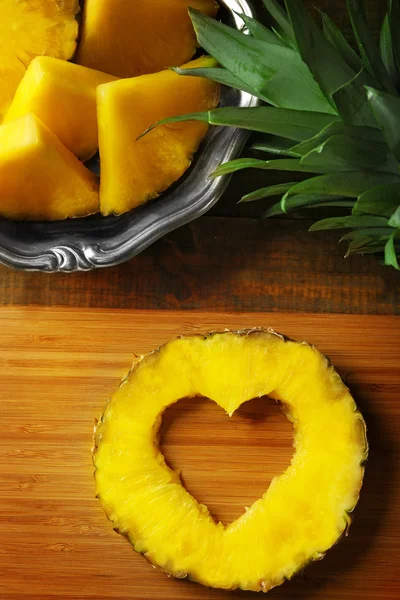 Ahşap kesme tahtası üzerinde kalp şekil dışarı kesim ile sulu ananas dilim — Stok fotoğraf