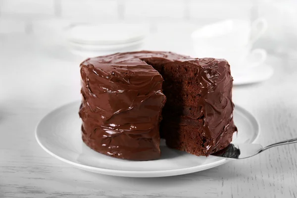 Čokoládový dort na desce s odříznutý kus na rozostřený pozadí, detail — Stock fotografie