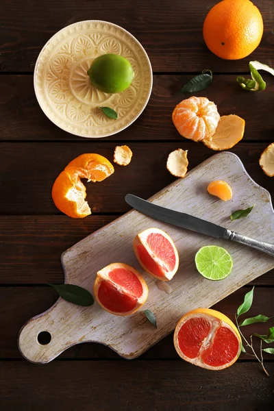 Verse citrusvruchten met groene bladeren op houten tafel, bovenaanzicht — Stockfoto
