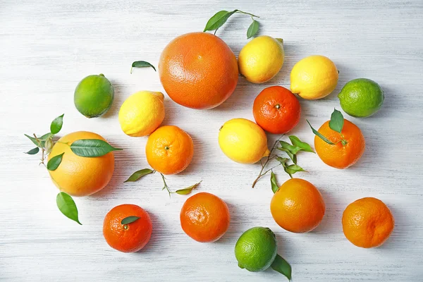 Fresh citrus fruits with green leaves on wooden background — Stock Photo, Image