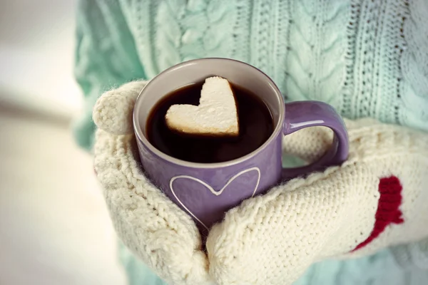 Kobiece ręce w ciepłe rękawice trzymając kubek gorącej kawy z serca Zefir, z bliska — Zdjęcie stockowe