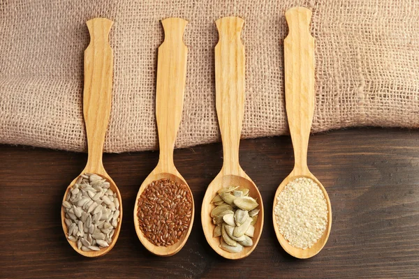 Sésamo, linho, sementes de abóbora e girassol em colheres de madeira na mesa, close-up — Fotografia de Stock