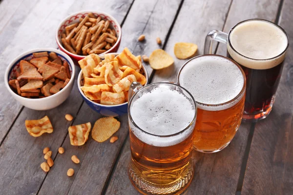 Various types of beer and snacks on wooden table — Stock Photo, Image