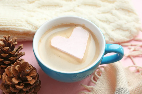 Coupe de cappuccino chaud avec guimauve cardiaque et vêtements chauds sur fond rose, gros plan — Photo