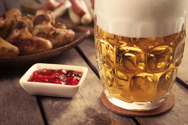 Glas Bier, Chicken Wings und Grillwürste auf Holztisch, Nahaufnahme — Stockfoto