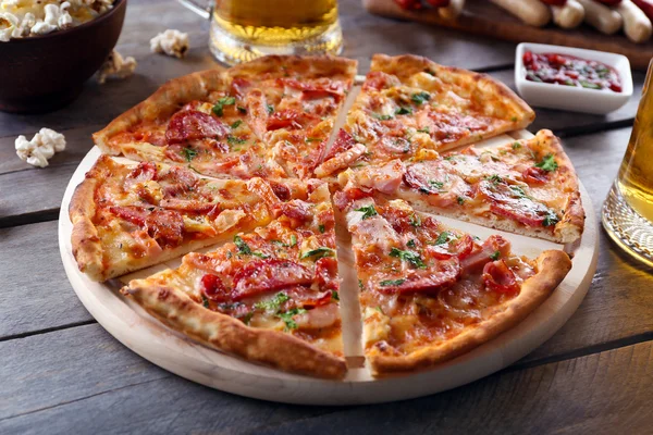 Pizza affettata e bicchiere di birra sul tavolo di legno, primo piano — Foto Stock