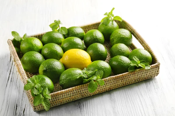 Rotting korg av limefrukterna och en citron på bord — Stockfoto