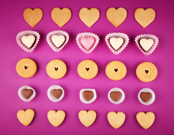 Biscuits savoureux et bonbons pour la Saint Valentin sur fond violet — Photo