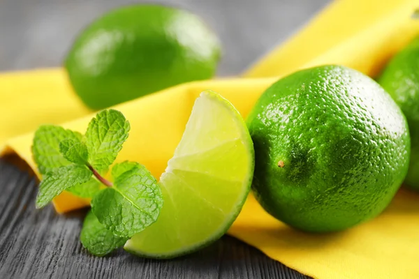 Fresh limes and mint on yellow napkin — Stock Photo, Image