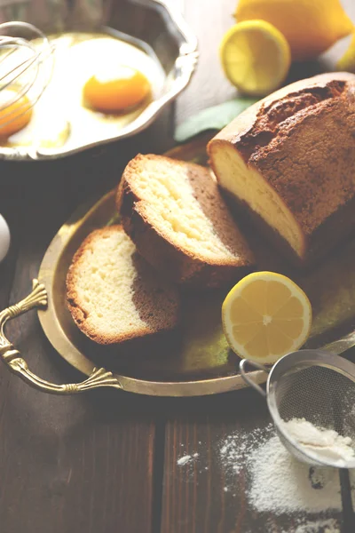 Delicioso pan de pastel dulce en bandeja de metal con limones en primer plano de mesa de madera —  Fotos de Stock