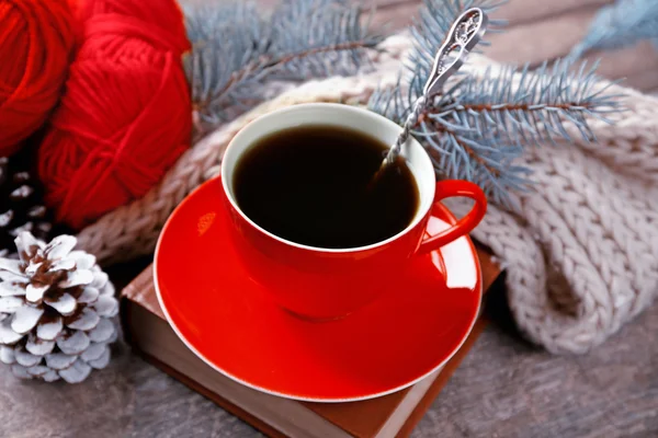 Cup of hot drink with knitted warm winter scarf on old wooden table — Stock Photo, Image