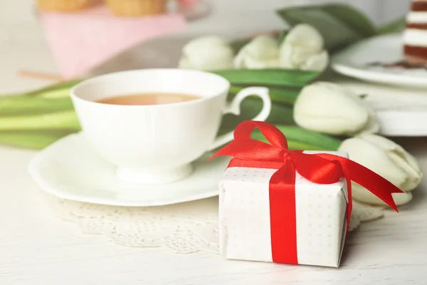 Caixa de presente com tulipas e xícara de chá na mesa de madeira closeup — Fotografia de Stock