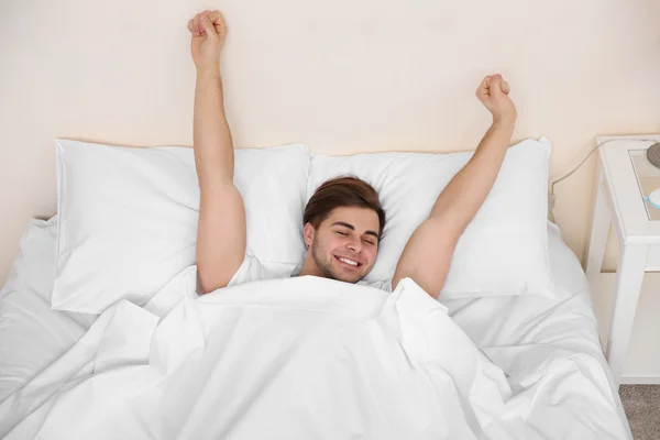 Young man stretching on bed — Stock Photo, Image