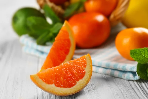 Pieces of orange on light wooden background — Stock Photo, Image