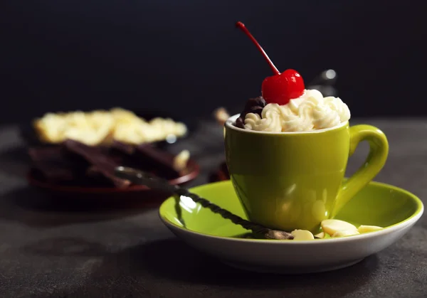 Gâteau au chocolat dans une tasse verte avec crème fouettée et une cerise sur le dessus, fermer — Photo