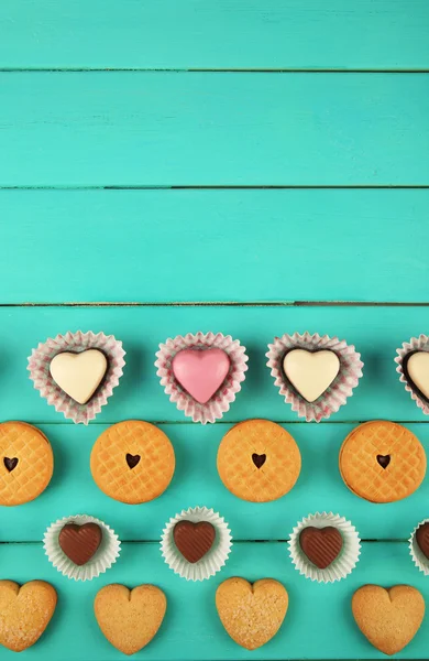 Il concetto di San Valentino. Composizione di deliziose caramelle al cioccolato e gustosi biscotti su sfondo di legno turchese — Foto Stock