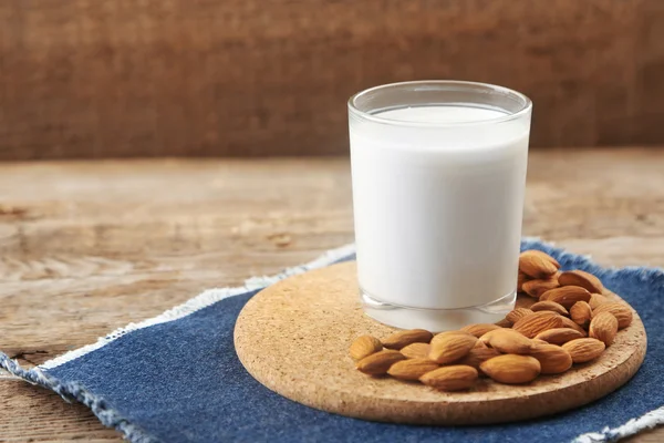 Cup of milk and almond nuts on table — Stock Photo, Image