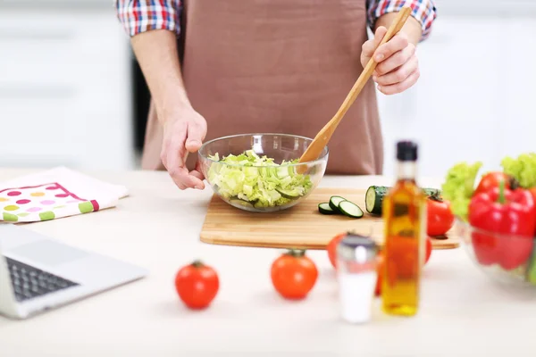 Mann kocht Gemüsesalat in Küche — Stockfoto