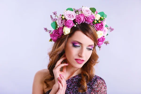 Hermosa mujer joven con diadema floral sobre un fondo gris —  Fotos de Stock