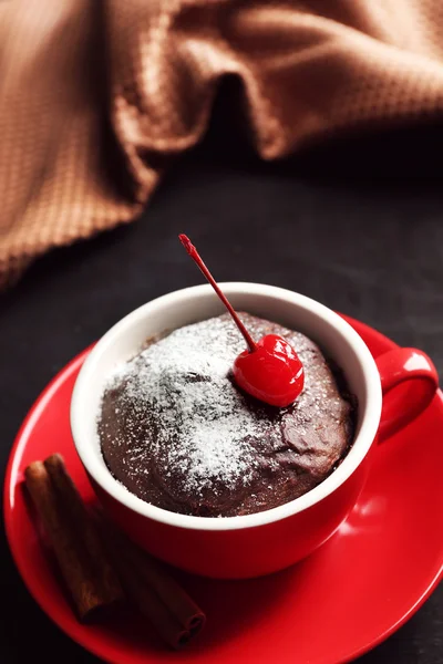 Pastel de chocolate en una taza roja con una cereza sobre un fondo de madera, de cerca —  Fotos de Stock