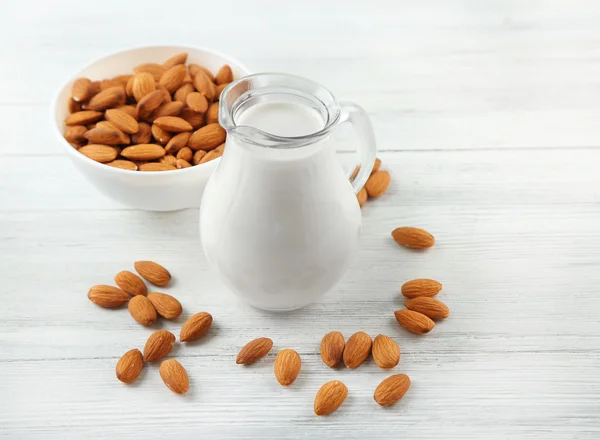 Jug of milk and almond nuts on table — Stock Photo, Image