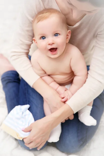 Woman dresses loving baby — Stock Photo, Image