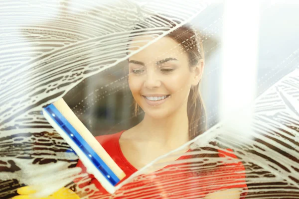 Jovem mulher lavando janela de vidro com esponja esfregona dentro — Fotografia de Stock
