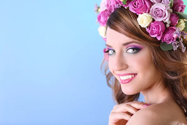 Όμορφη νεαρή γυναίκα που φοράει floral στήριγμα κεφαλής σε μπλε φόντο — Φωτογραφία Αρχείου