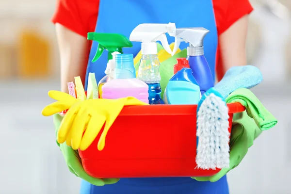 Concepto de limpieza. Mujer joven sostiene lavabo con líquidos de lavado y trapos en las manos, de cerca — Foto de Stock