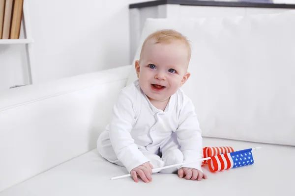 Lindo bebé en un sofá blanco con bandera americana, primer plano — Foto de Stock