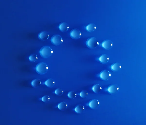 Círculo feito de gotas de água no fundo azul — Fotografia de Stock
