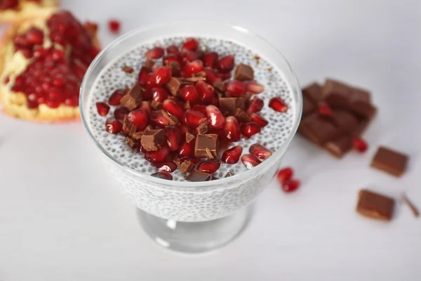 Chia seeds pudding with pomegranate grains and chocolate chips in glass saucer on white background — Stock Photo, Image