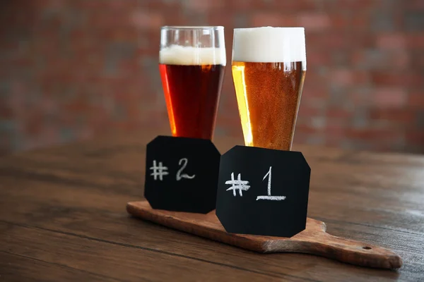 Glasses with different sorts of craft beer and numbering on wooden tray — Stock Photo, Image