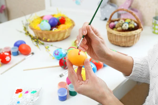Kvinnliga händer måla påskägg på bordet inomhus — Stockfoto