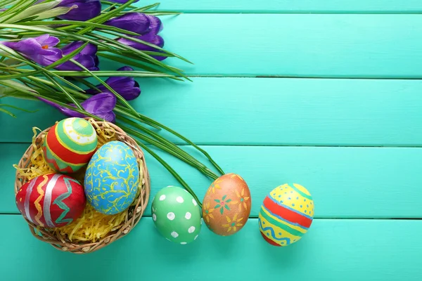 Színes húsvéti tojás és a sáfrány virágok fából készült háttér — Stock Fotó