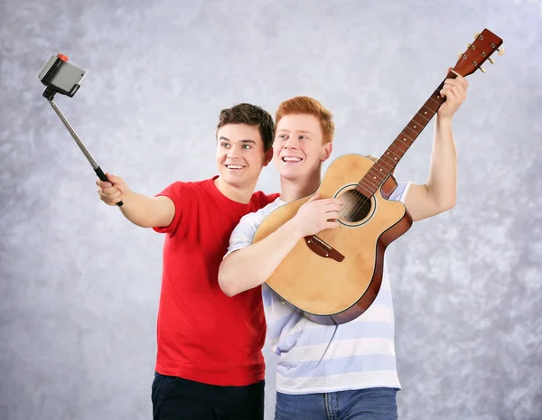 Два мальчика-подростка с гитарой используют палку для фото — стоковое фото