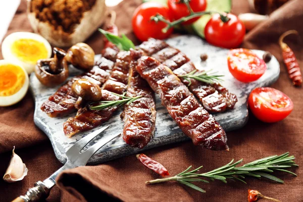 Grillet oksekød med grøntsager på skærebræt - Stock-foto