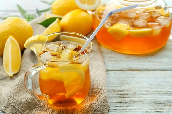 Glass of ice lemon tea and pot on wooden table — Stock Photo, Image