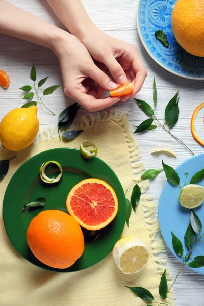 Mulher segurando fatia de tangerina e vários citrinos em pratos — Fotografia de Stock