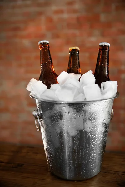 Botellas de vidrio marrón de cerveza en cubo de hielo sobre fondo de pared de ladrillo —  Fotos de Stock