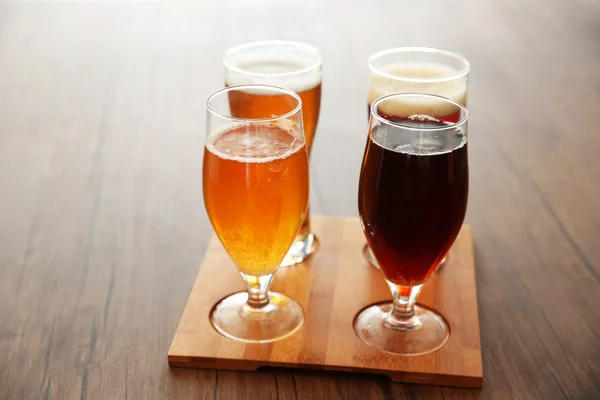 Glasses with different sorts of craft beer on wooden tray — Stock Photo, Image