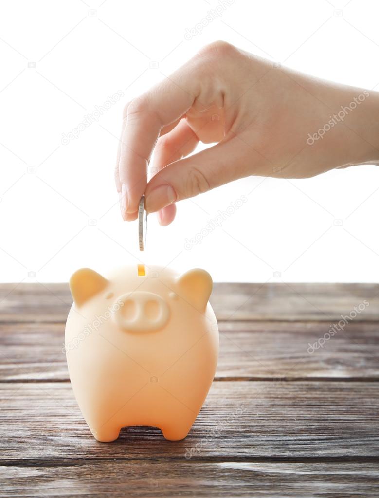 hand putting coin into piggy bank 