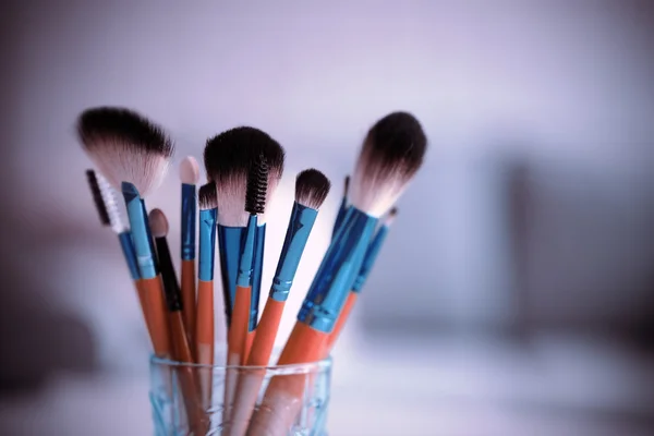 Cosmetic brushes in glass on bright background — Stock Photo, Image